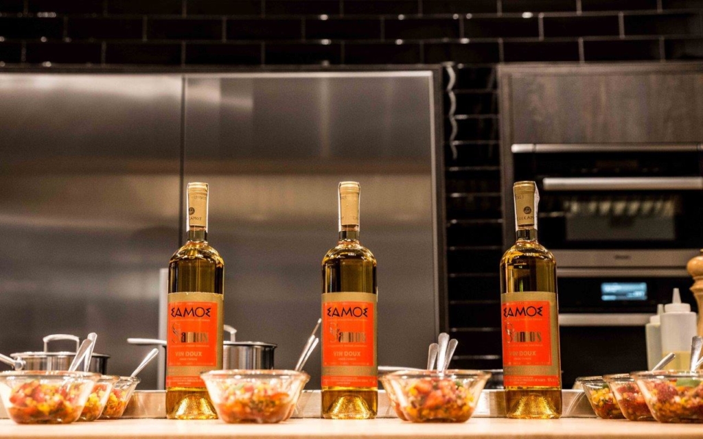 A tray of food and a bottle of samos wine in a commercial kitchen