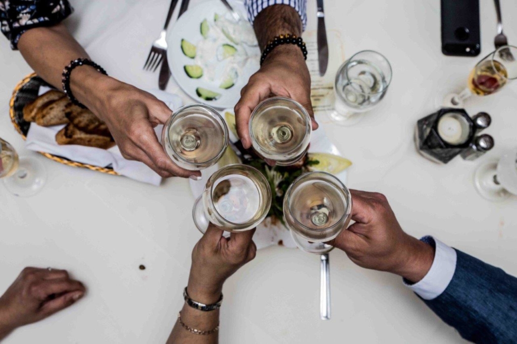 A group of people posing for photoshoot sitting at a table with a wine glasses